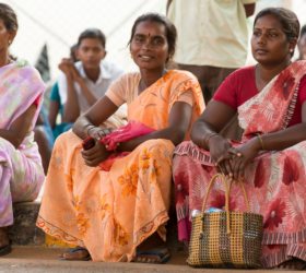 3 Indian women sitting on a curb