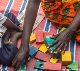 Caretaker from Rwanda, for her community's Early Childhood Development Program, plays with two boys.