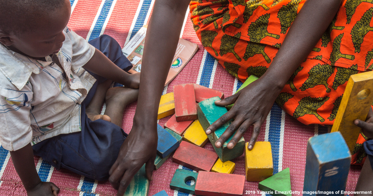 Caretaker from Rwanda, for her community's Early Childhood Development Program, plays with two boys.