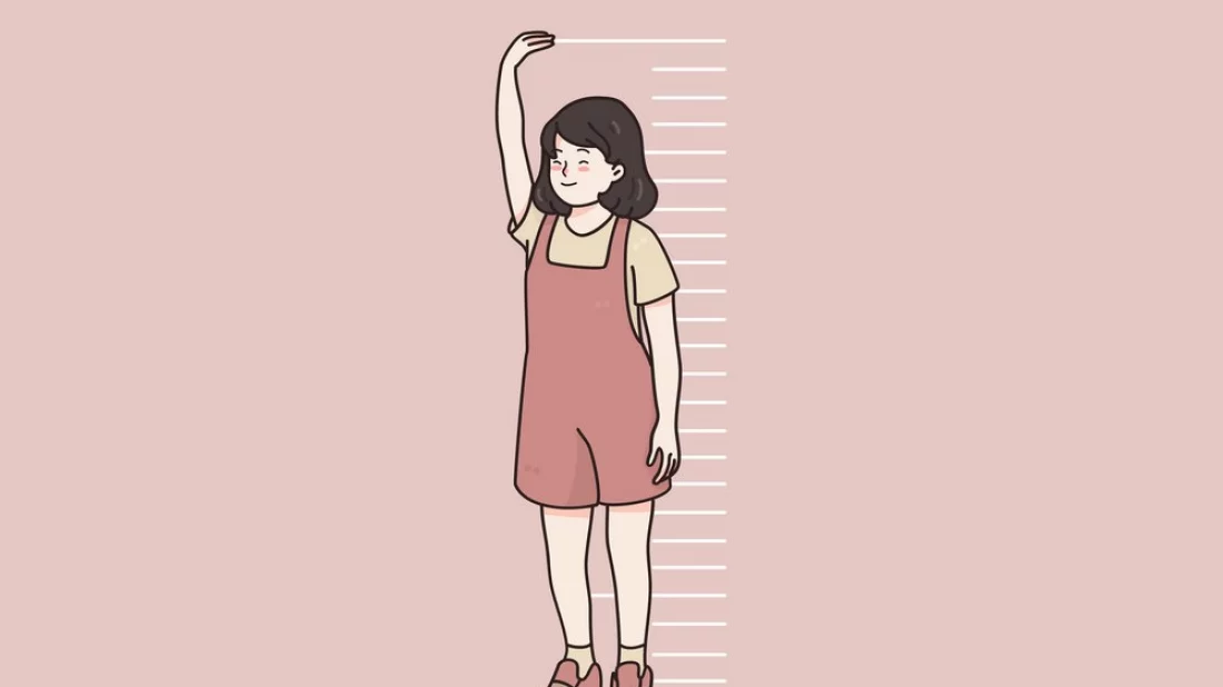 Girl measuring herself against a wall.