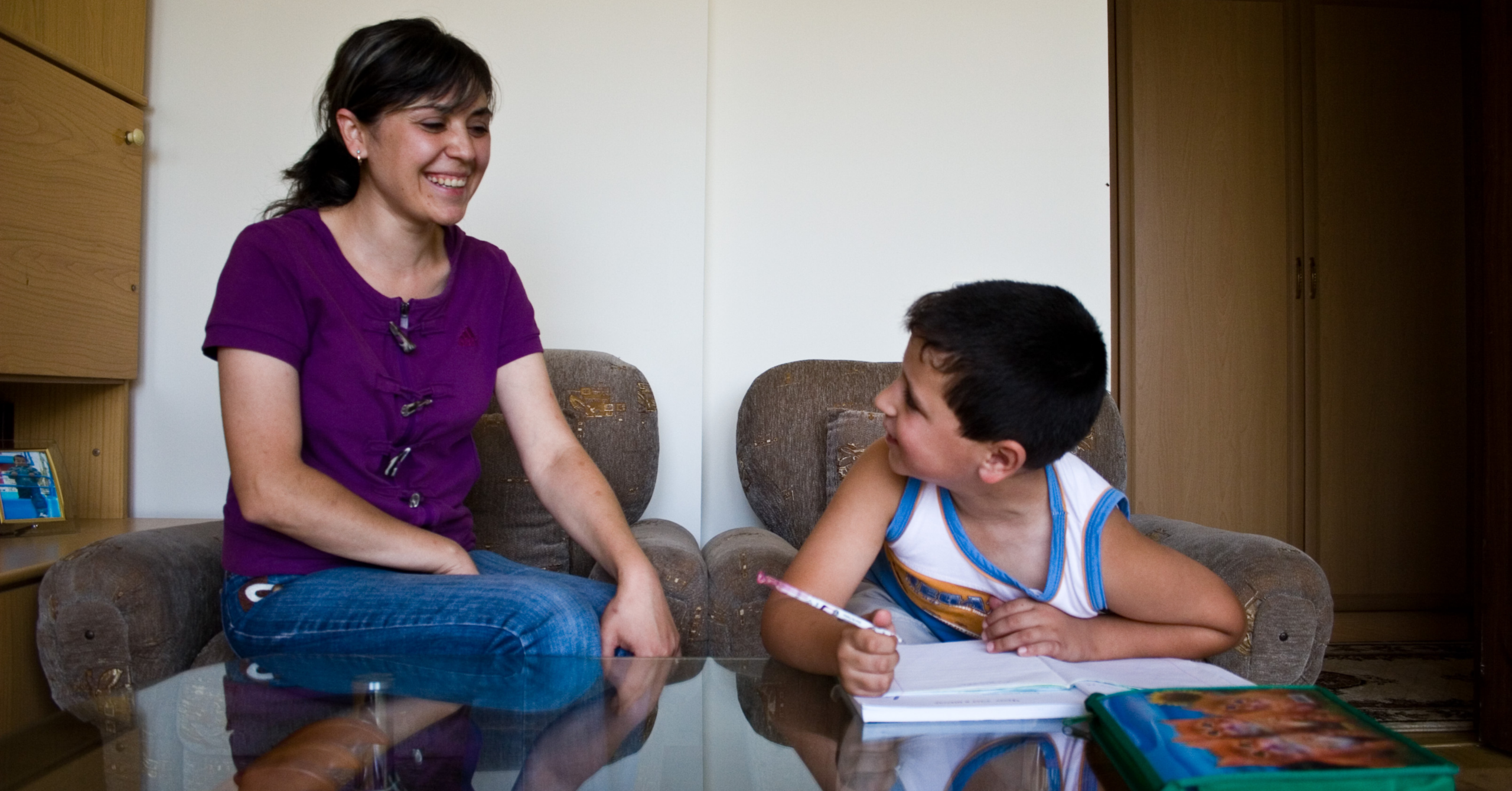 Mother helps her son with his homework in their home in Armenia.