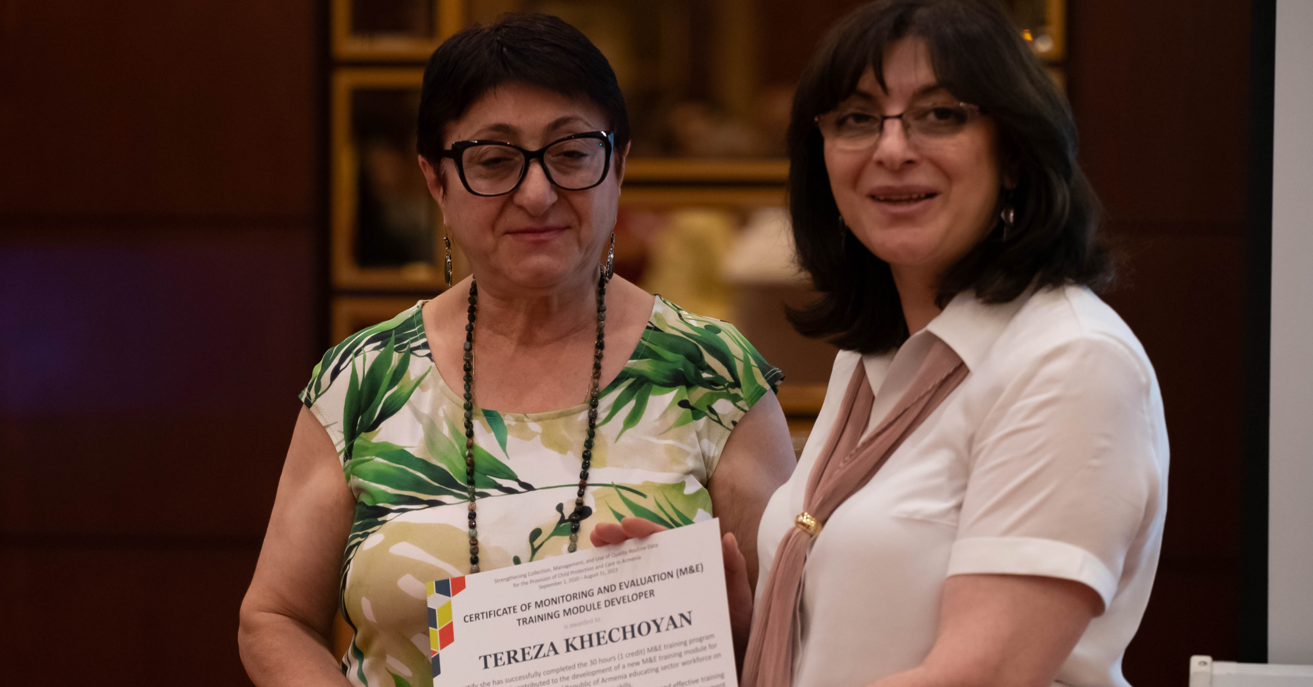 Photo of D4I’s Armenia-based M&E expert presenting a certificate recognizing participation in M&E module development to a staff member.