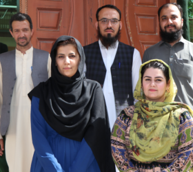 Photo showing the Afghanistan team (3 men and 2 women) standing in front of a doorway.